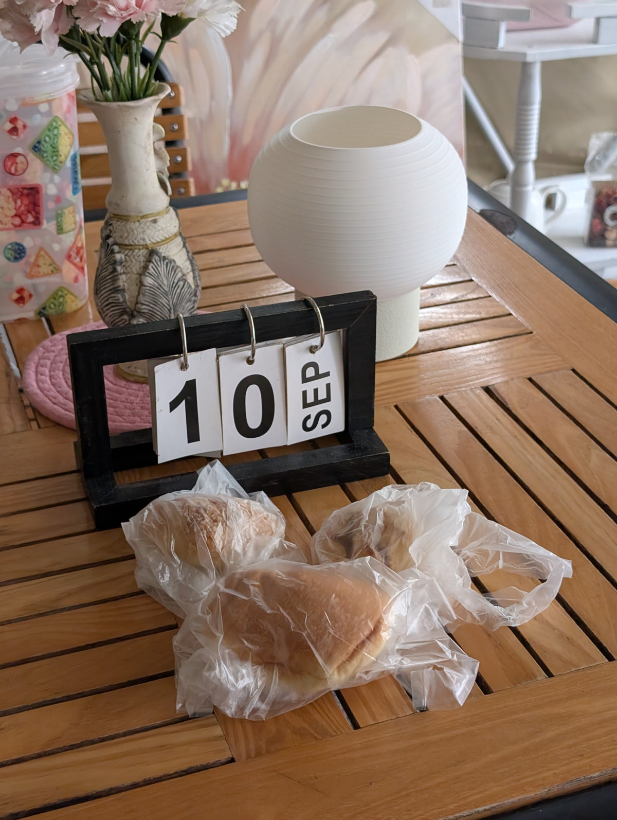 KAMI on a wooden table beside a desk calendar and flowers
