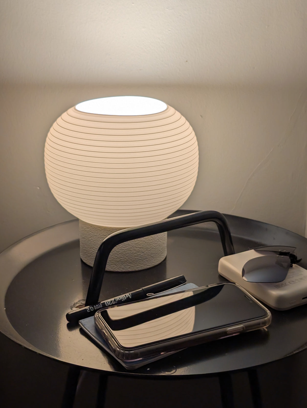 KAMI lamp lit on a round black side table