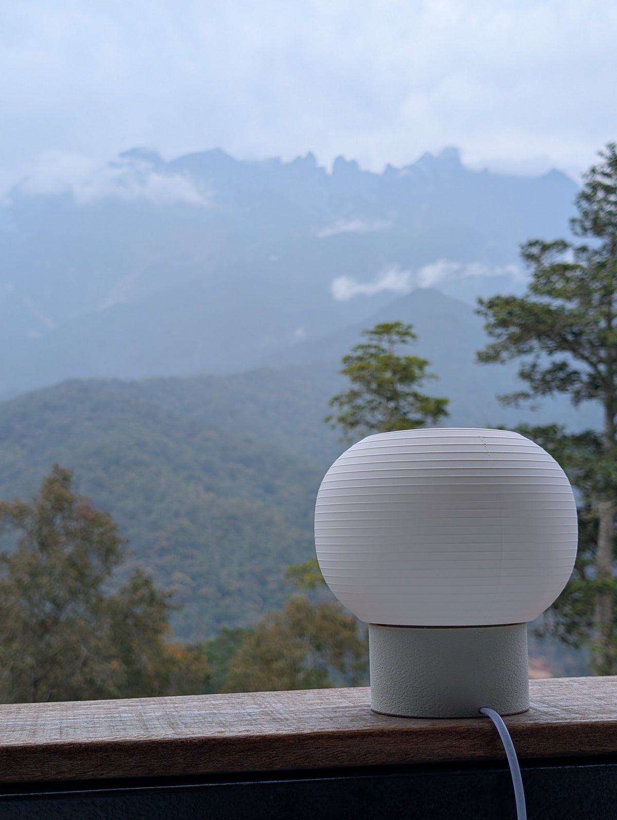 KAMI on a balcony ledge with mountains behind