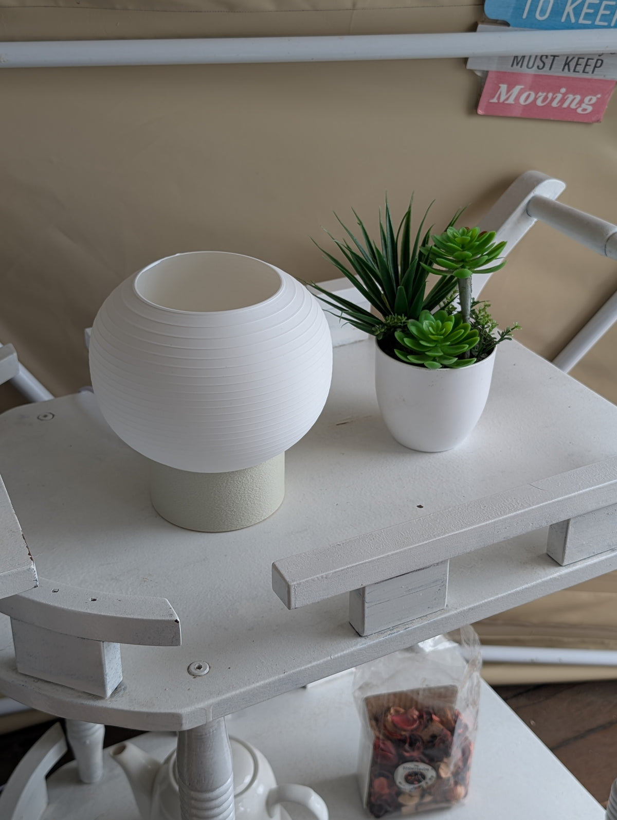 KAMI on a white shelf next to a small plant