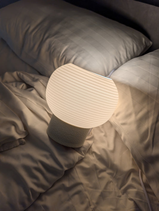 KAMI lamp lit warm on a bed at night